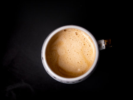 A white coffee cup with foam on top. The foam is brown and the cup is almost emptyの写真素材
