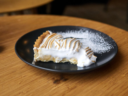 Slice of pie with whipped cream on a plate. The pie is cut in half and the whipped cream is spread on topの写真素材