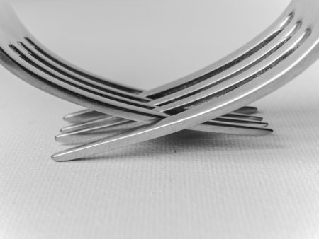 Two forks are crossed over each other, creating a unique and interesting design. Concept of creativity and playfulness, as the forks are not being used for their intended purpose of eating. Insteadの写真素材
