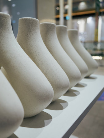 Row of white vases are lined up on a shelf. The vases are all different shapes and sizes, but they all have a similar color and textureの写真素材