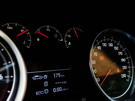 A car dashboard with a speedometer showing a speed of 0 km/h. The car is also showing a low fuel...