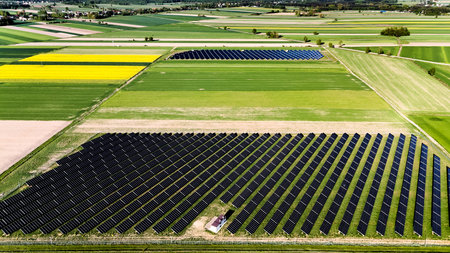 Field of solar panels is shown in the image. The panels are arranged in rows and are spread across...