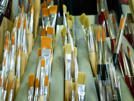 Row of paintbrushes are lined up on a shelf. The brushes are of different sizes and colorsの写真素材