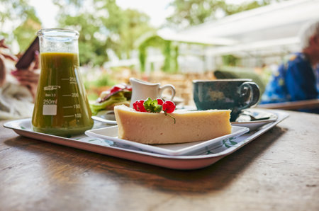 Tray of food with a slice of cake and a glass of juice. The tray is on a wooden tableの写真素材