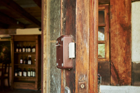 Wooden door with a lock on it. The door is in front of a wine cellar. The wine cellar has a lot of...