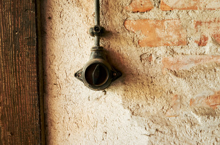 Switch is hanging from a wall. The switch is old and rusted. The wall is made of bricksの写真素材