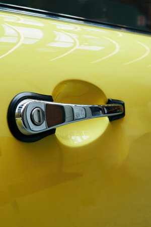 Yellow car door handle with a silver knob. The handle is black and has a silver knob. Phone...