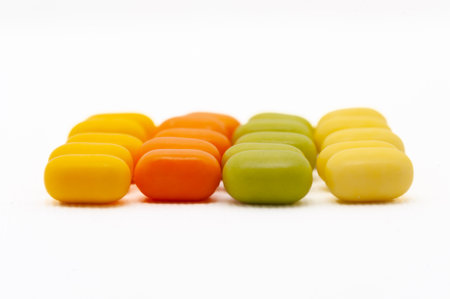 A row of candy is shown in different colors. The candy is yellow, green, and orange