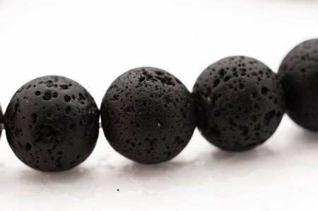 A black stone bead is shown in the image. It is the center of a row of four beads