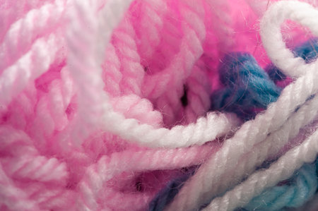A bunch of yarn with pink, white, and blue colors. The pink and white yarn is twisted together