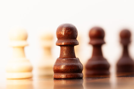 A black and white chess piece is standing out on a board with other pieces. It is a pawn, which is...