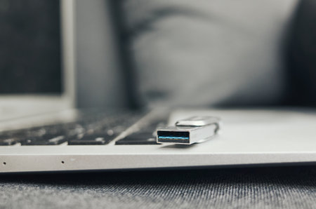 Laptop with a USB cable on it. The laptop is open and the cable is plugged into itの写真素材