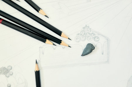 Drawing of a cake with a piece of chocolate on it. There are five pencils on the tableの写真素材