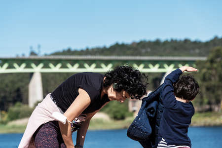 young Caucasian woman with her daughter after yoga training with river and bridge in the backgroundの写真素材