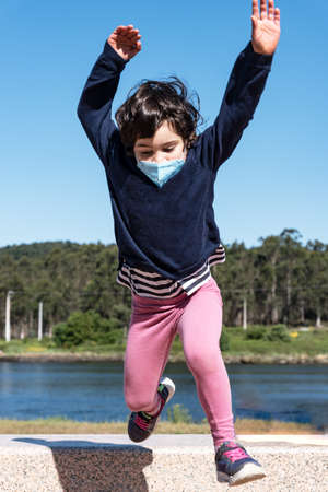 caucasian child jump at grass from the bench on the promenade with smile faceの写真素材