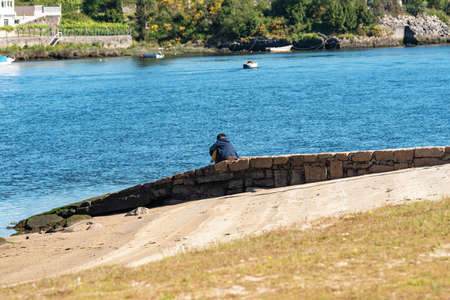caucasian boy sit alone in old harbour at beach think seen riverの写真素材