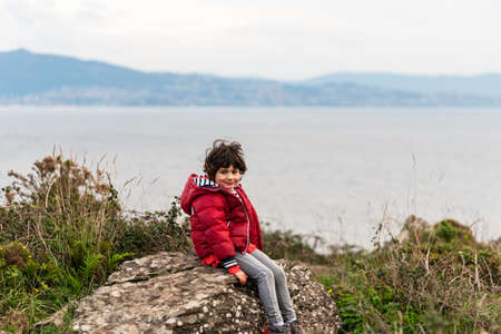 a caucasian girl sitting on a rock with the bay and the city in the background.の写真素材