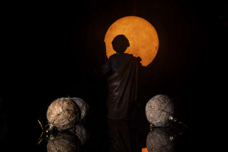 christmas scene figurine of saint joseph looking at the orange full moon between christmas balls with his back to the cameraの写真素材