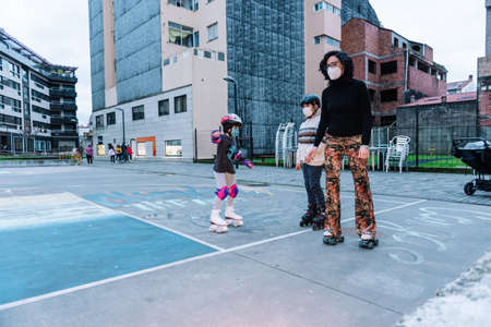 caucasian woman with her children skating in a city park