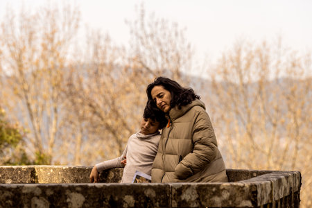 Caucasian mother and son embrace with sad look outdoorの写真素材