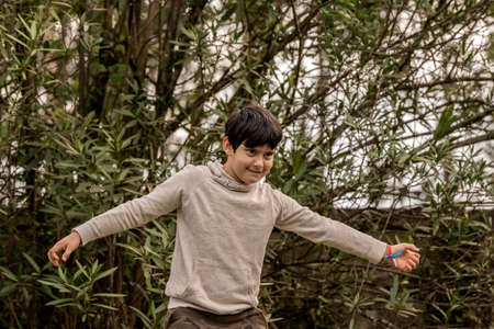 one little boy dancing in the forest with his arms open and smilingの写真素材