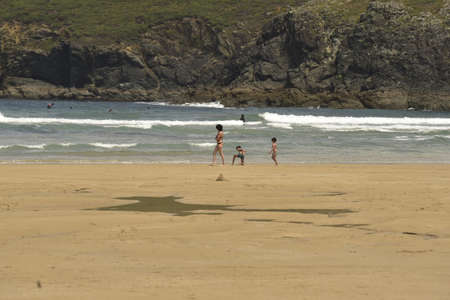 Caucasian mother and two children stroll along the beach watching the sea.の写真素材