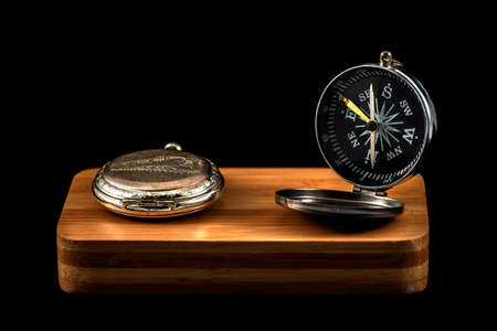 antique compass and pocket watch on wood with black background