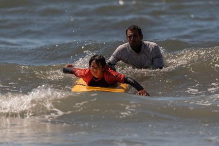 Aveiro, Portugal. august 19 - 2022: Surf lessons for children first class in the beach with diversity people. Take the first wave.のeditorial素材