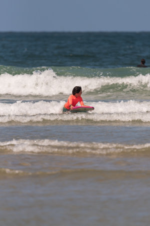 boy with orange equipment and bodyboard practices in the waves of Aveiro beach