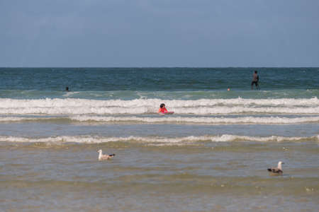 boy with orange equipment and bodyboard practices in the waves of Aveiro beach