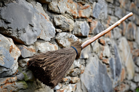 a broom leaning against a stone wallの素材