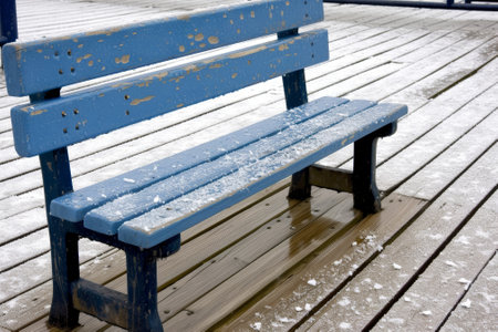Snow dusted blue bench in a winter settingの素材