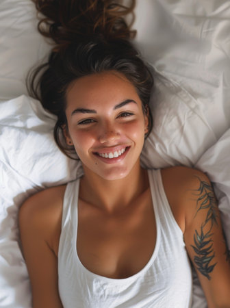 Young woman smiling while lying in bedの素材