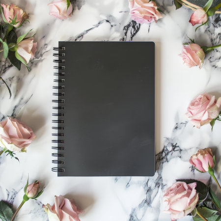 black notebook on marble background with pink rosesの素材
