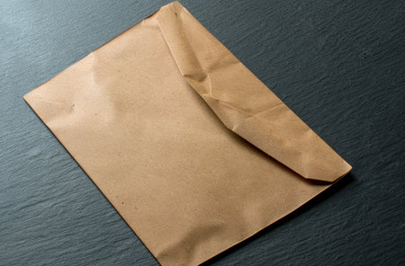 Crumpled brown paper envelope on dark backgroundの素材