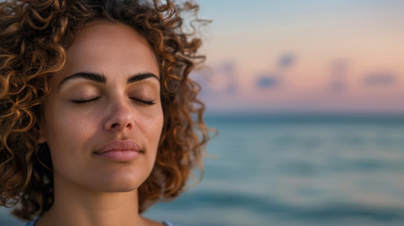 woman with curly hair enjoying peaceful moment by the seaの素材