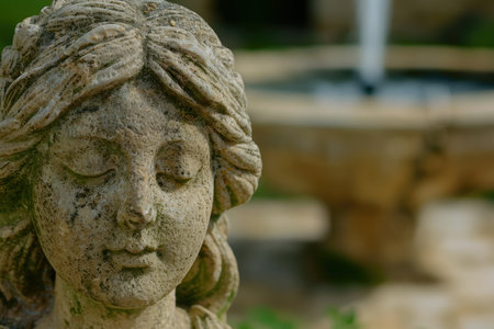 weathered stone face sculpture in gardenの素材