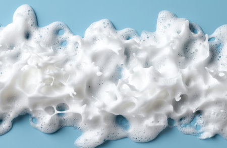Fluffy white soap suds on blue backgroundの素材