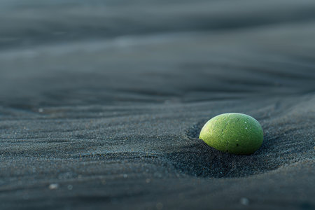 Lone tennis ball on dark sandy beachの素材
