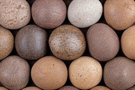 Assortment of smooth river rocks in various shades of brown and grayの素材