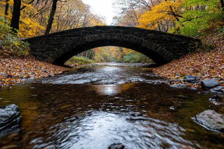Scenic autumn landscape with a stone bridge over a flowing riverの素材