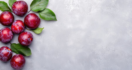 Fresh plums with leaves on a light backgroundの素材