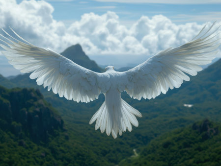 Majestic white dove with outstretched wings soaring over mountain landscapeの素材
