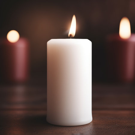 Glowing white candle on a wooden surfaceの素材