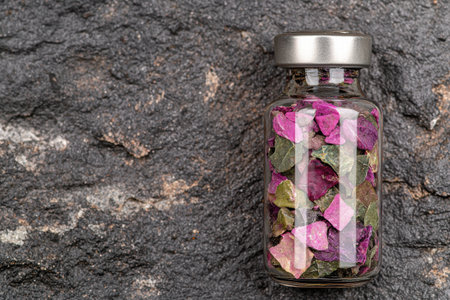Dried flowers in glass jar on rocky surfaceの素材