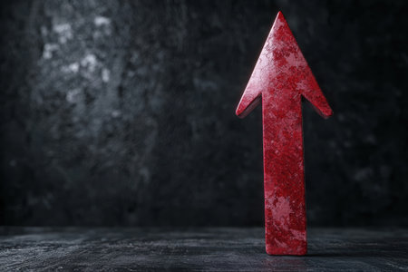 Dramatic red arrow pointing upwards on dark backgroundの素材