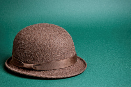 Vintage brown felt hat with ribbon on green backgroundの素材