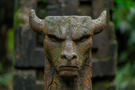 Weathered stone gargoyle statue in a lush green forestの素材