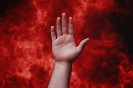 hand reaching out in a fiery red backgroundの素材