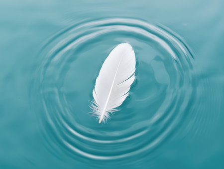Delicate feather floating on serene water surfaceの素材